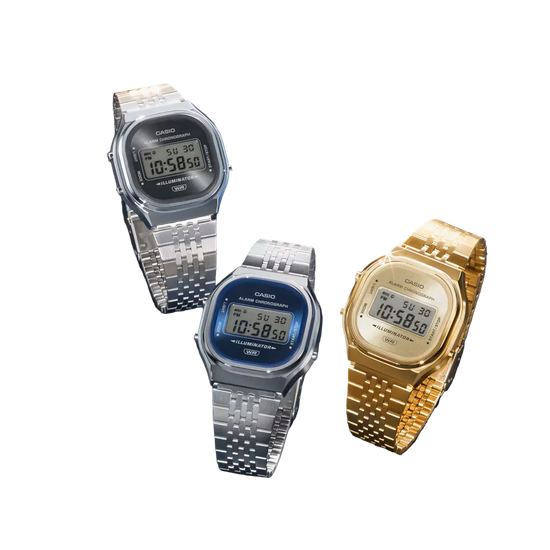 Three Casio digital wristwatches with metal link bands are arranged on a dark textured background. One watch is silver with a black face, one is silver with a blue face, and one is gold with a cream face.